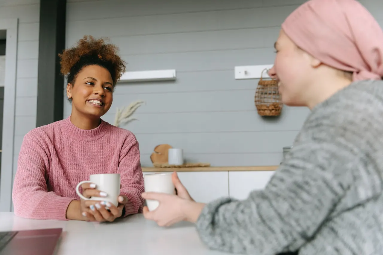 Zwei Frauen unterhalten sich bei einer Tasse Kaffee in einer hellen Küche
